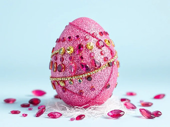 Pink glitter egg encrusted with pink ruby garnets, with spiral bands of Garnetts wrapped around in a helix with colors arranged as rainbow stripes