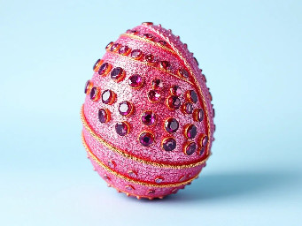 Pink glitter egg encrusted with pink ruby garnets, with spiral bands of Garnetts wrapped around in a helix with colors arranged as rainbow stripes