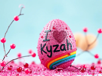 Pink glitter egg encrusted with pink ruby garnets, with spiral bands of garnetts wrapped around in a helix with colors arranged as rainbow stripes, with the words "I ♥️ Kyzah" painted on the egg